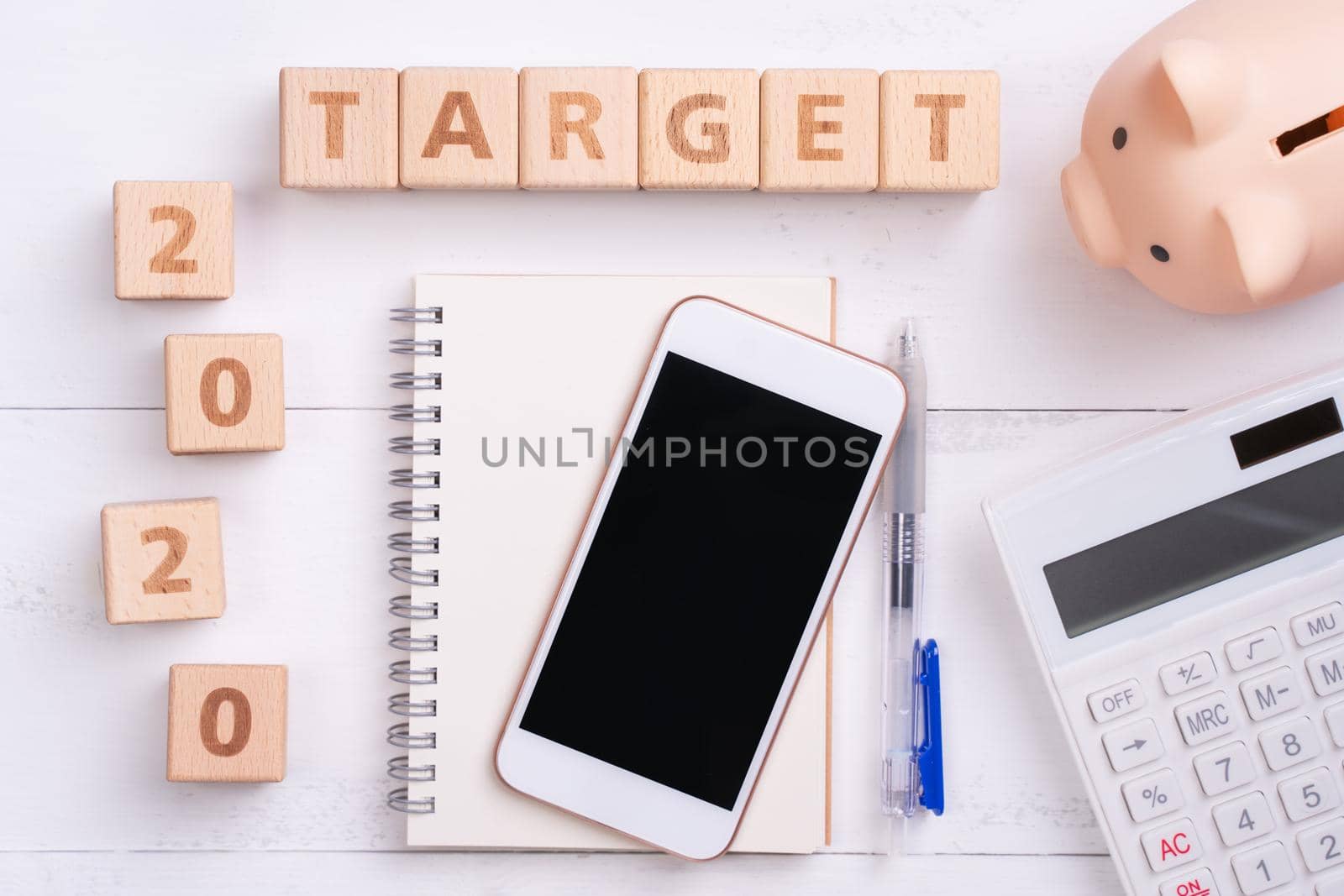 2020 goal, finance plan abstract design concept, wood blocks on white table background with piggy bank, cell phone, top view, flat lay, copy space.