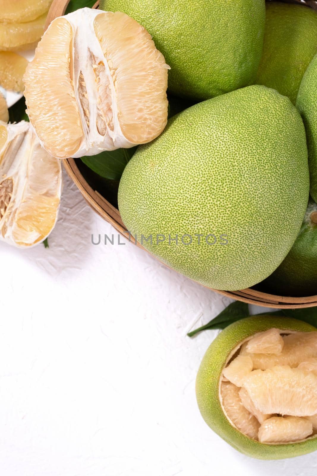 Fresh pomelo, pummelo, grapefruit, shaddock on white cement background in bamboo basket. Autumn seasonal fruit, top view, flat lay, tabletop shot.
