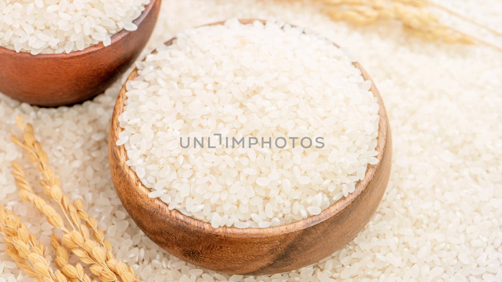 Raw white polished milled edible rice crop on white background in brown bowl, organic agriculture design concept. Staple food of Asia, close up.