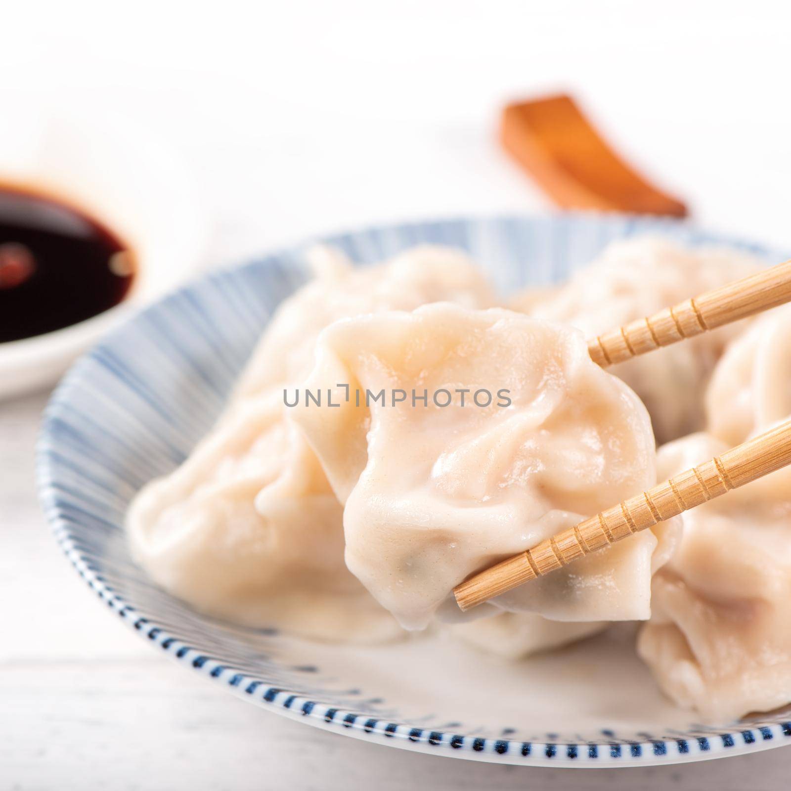 Fresh, delicious boiled pork, shrimp gyoza dumplings on white background with soy sauce and chopsticks, close up, lifestyle. Homemade design concept.