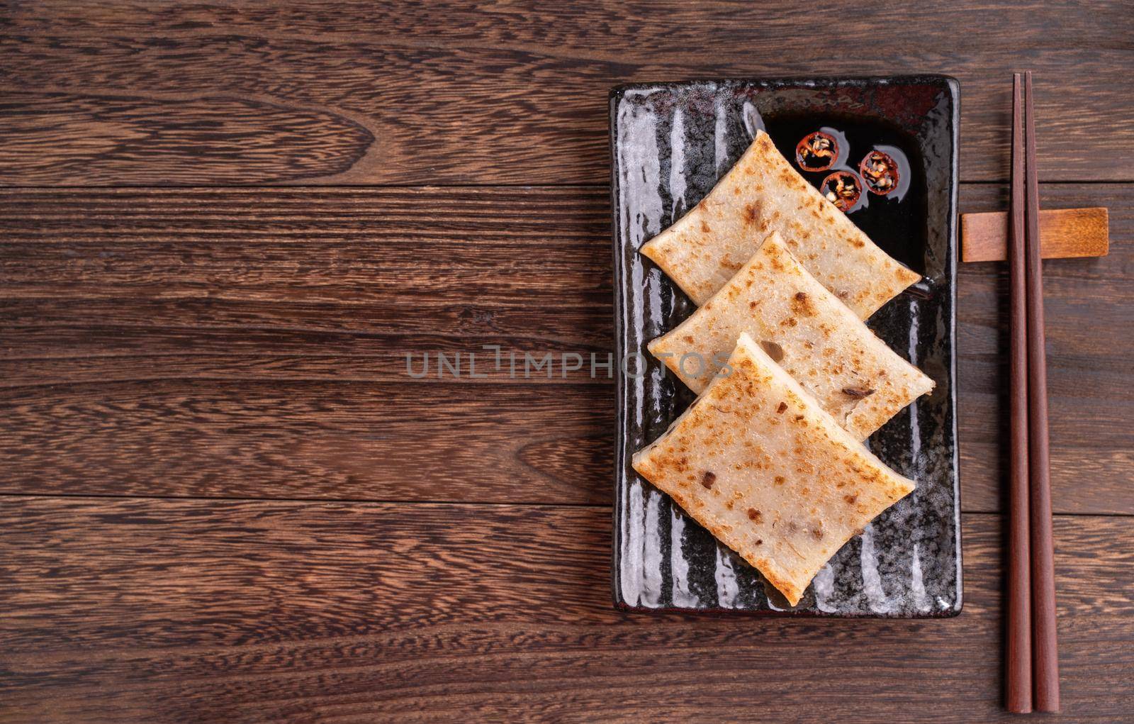 Delicious turnip cake, Chinese traditional radish cake in restaurant with soy sauce for new year's dishes, close up, copy space, top view, flat lay.