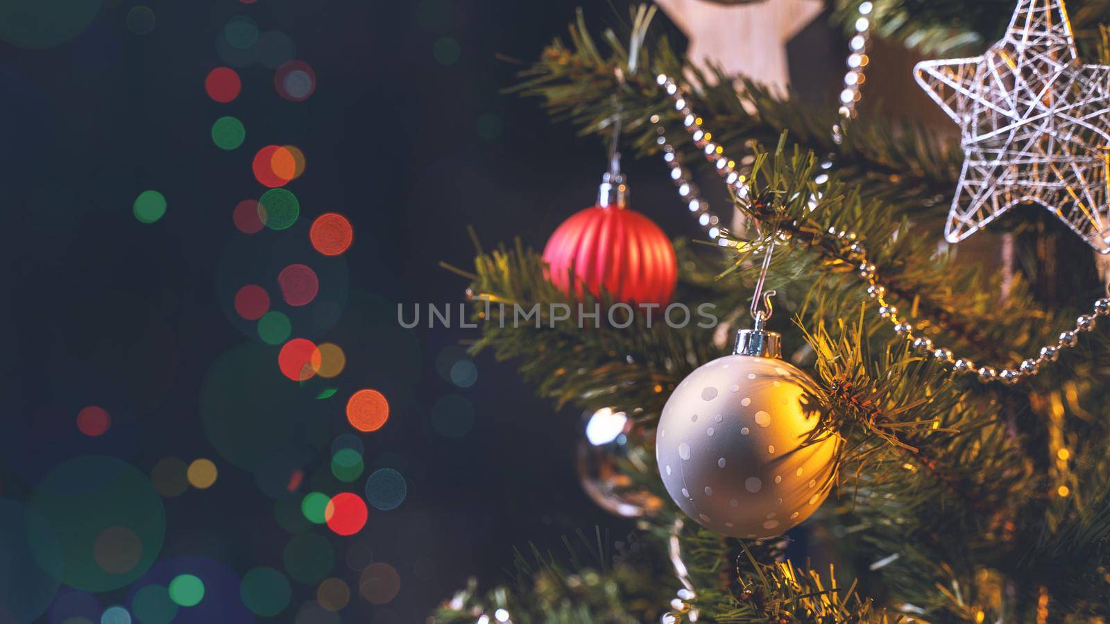 Beautiful Christmas decor concept, bauble hanging on the Christmas tree with sparkling light spot, blurry dark black background, macro detail, close up.