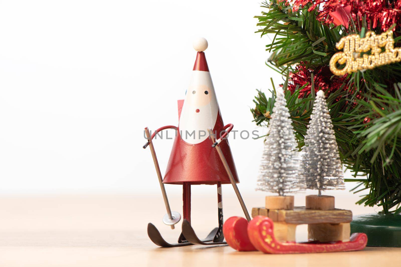 Decorated cute Christmas tree on a wooden floor with white background and toys, blank for festive design concept, close up.