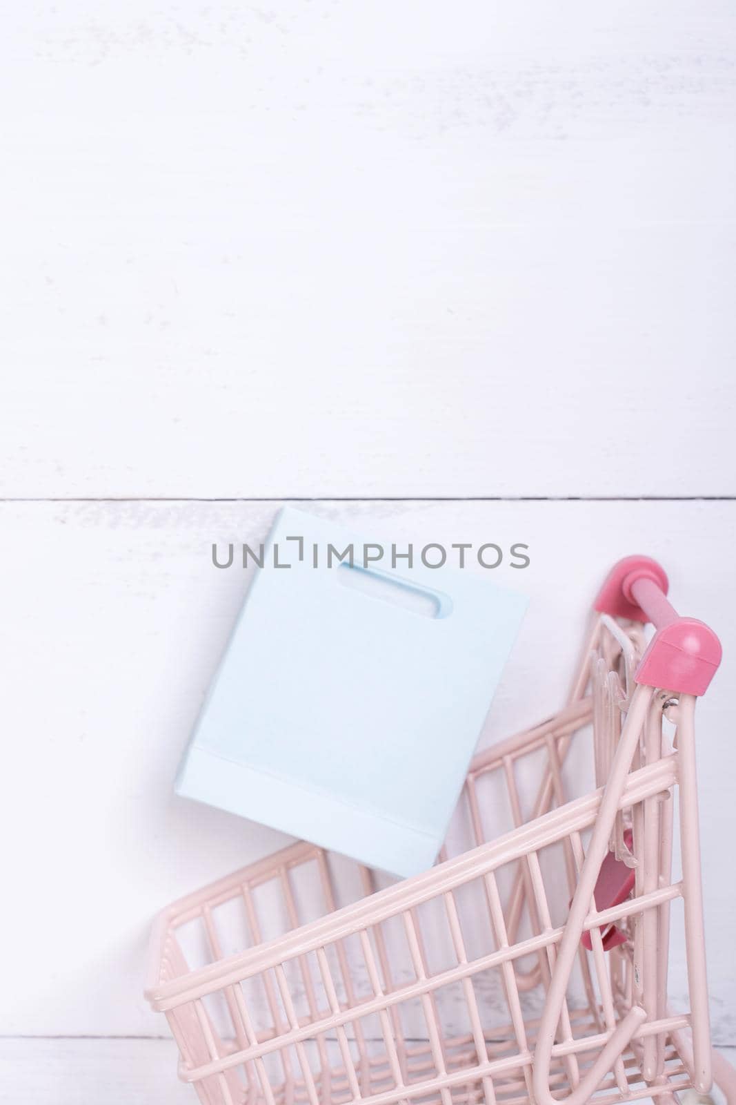 Abstract design element,annual sale,shopping season concept,mini cart with colorful paper bag on white wooden table background,top view,flat lay
