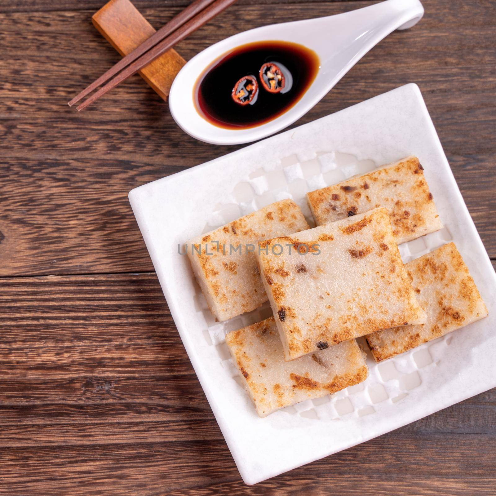 Delicious turnip cake, Chinese traditional radish cake in restaurant with soy sauce for new year's dishes, close up, copy space, top view, flat lay.