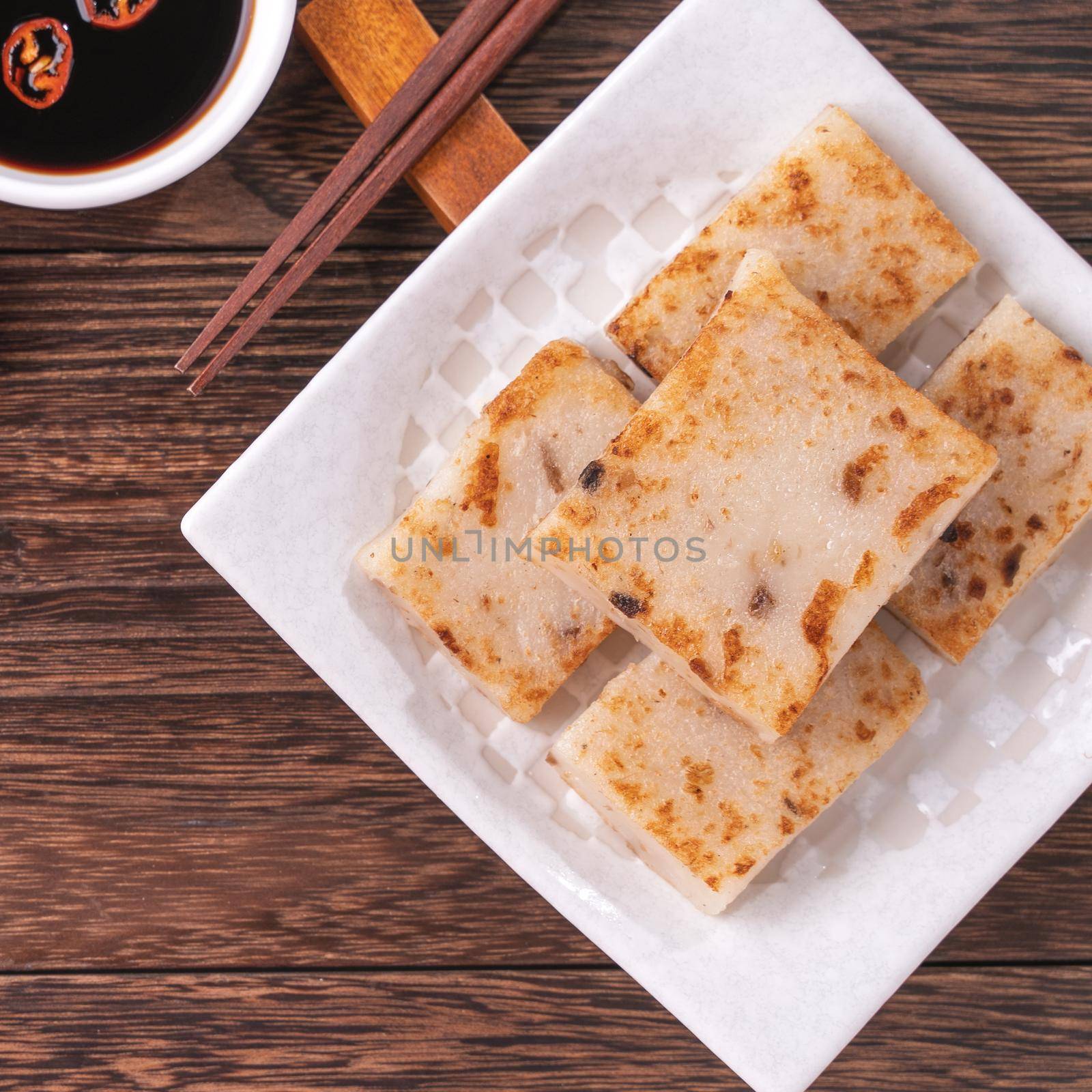 Delicious turnip cake, Chinese traditional radish cake in restaurant with soy sauce for new year's dishes, close up, copy space, top view, flat lay. by ROMIXIMAGE