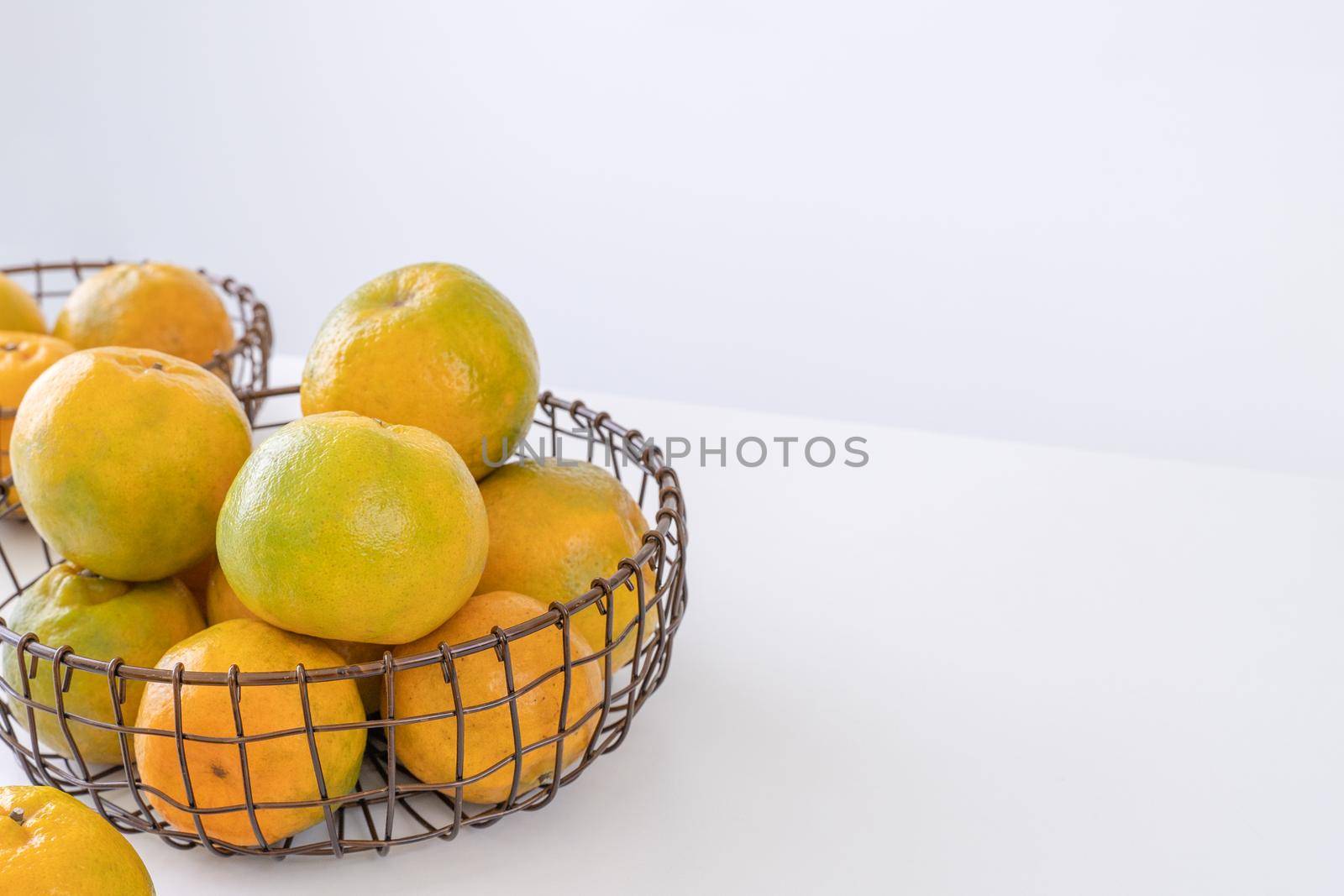 Beautiful peeled tangerines in a plate and metal basket isolated on bright white clean table in a modern contemporary kitchen island, close up.