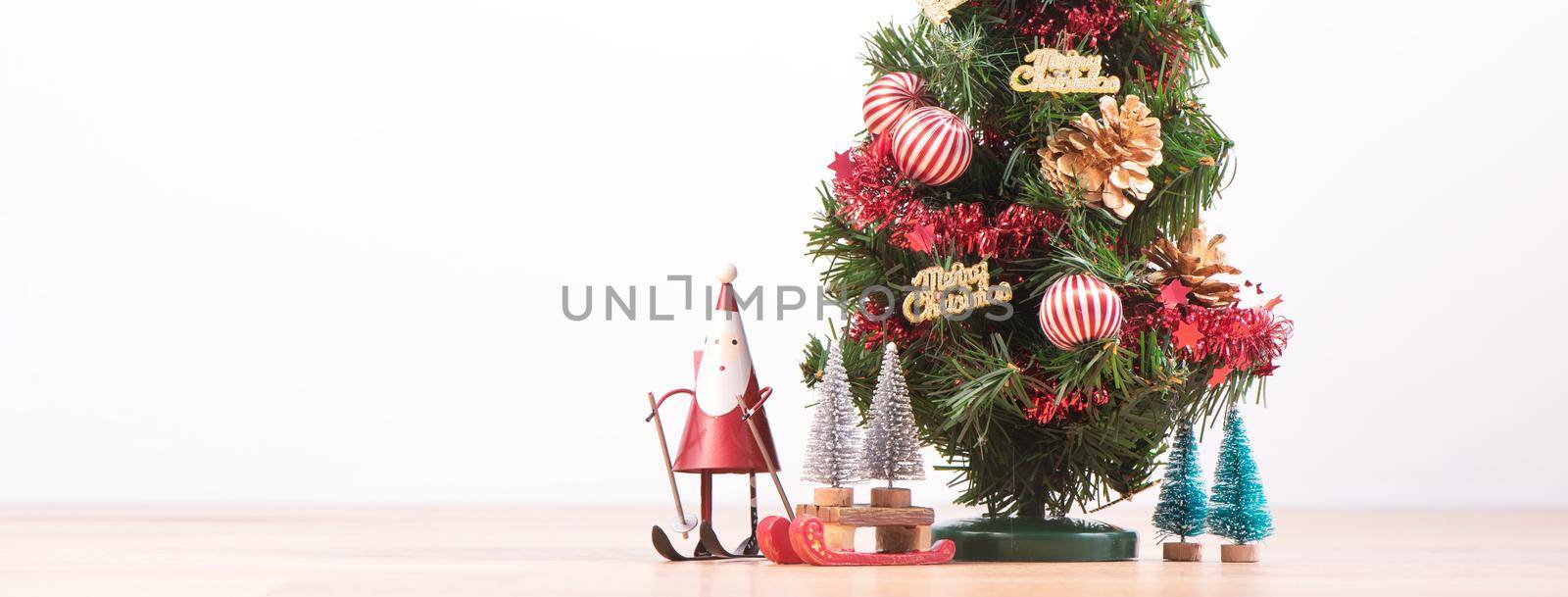 Decorated cute Christmas tree on a wooden floor with white background and toys, blank for festive design concept, close up.