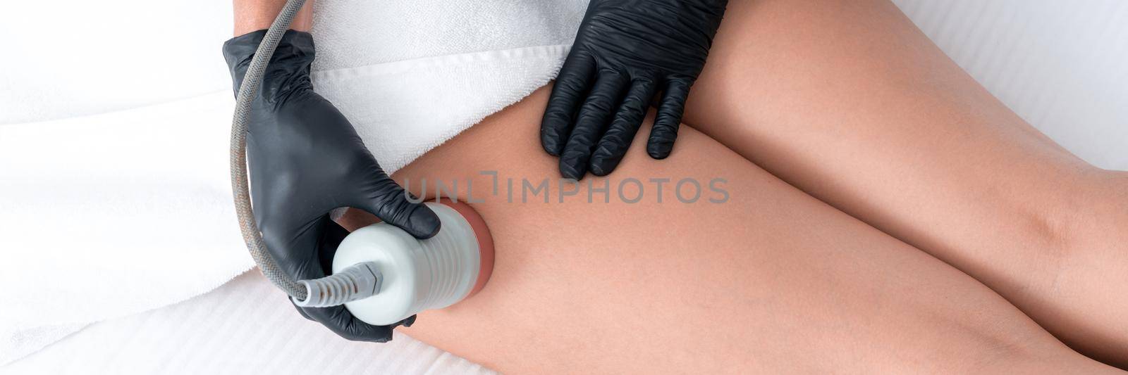 Beautiful woman having cavitation, procedure removing cellulite on legs and belly at beauty clinic by Mariakray