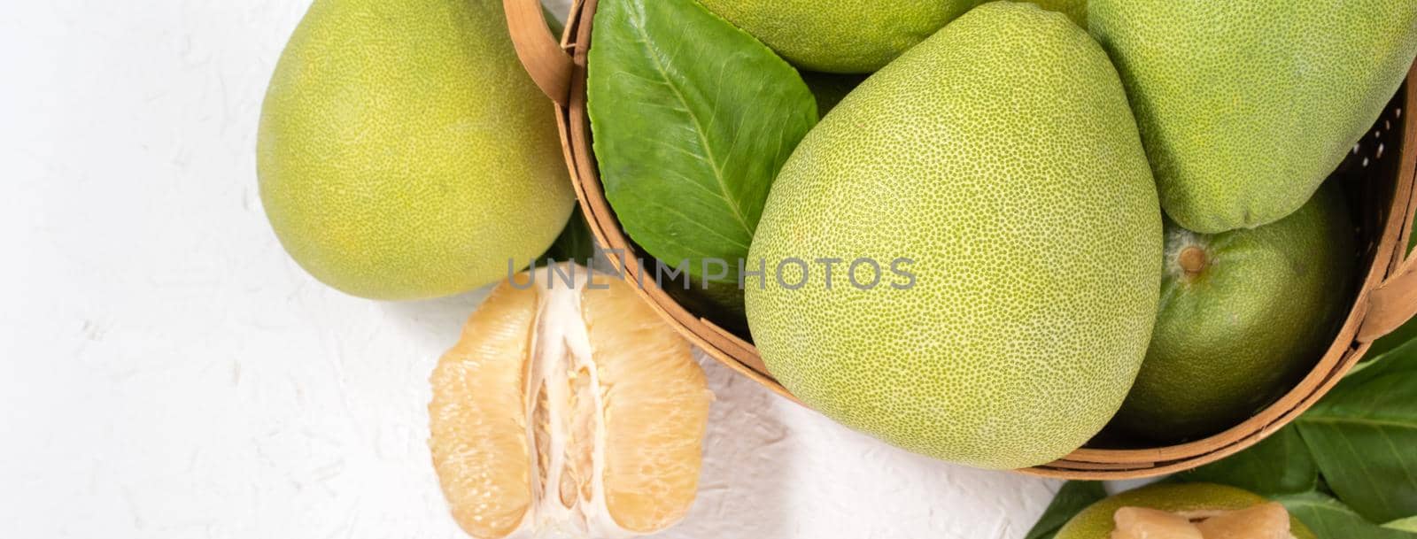 Fresh peeled pomelo, pummelo, grapefruit, shaddock on bright wooden background. Autumn seasonal fruit, top view, flat lay, tabletop shot.