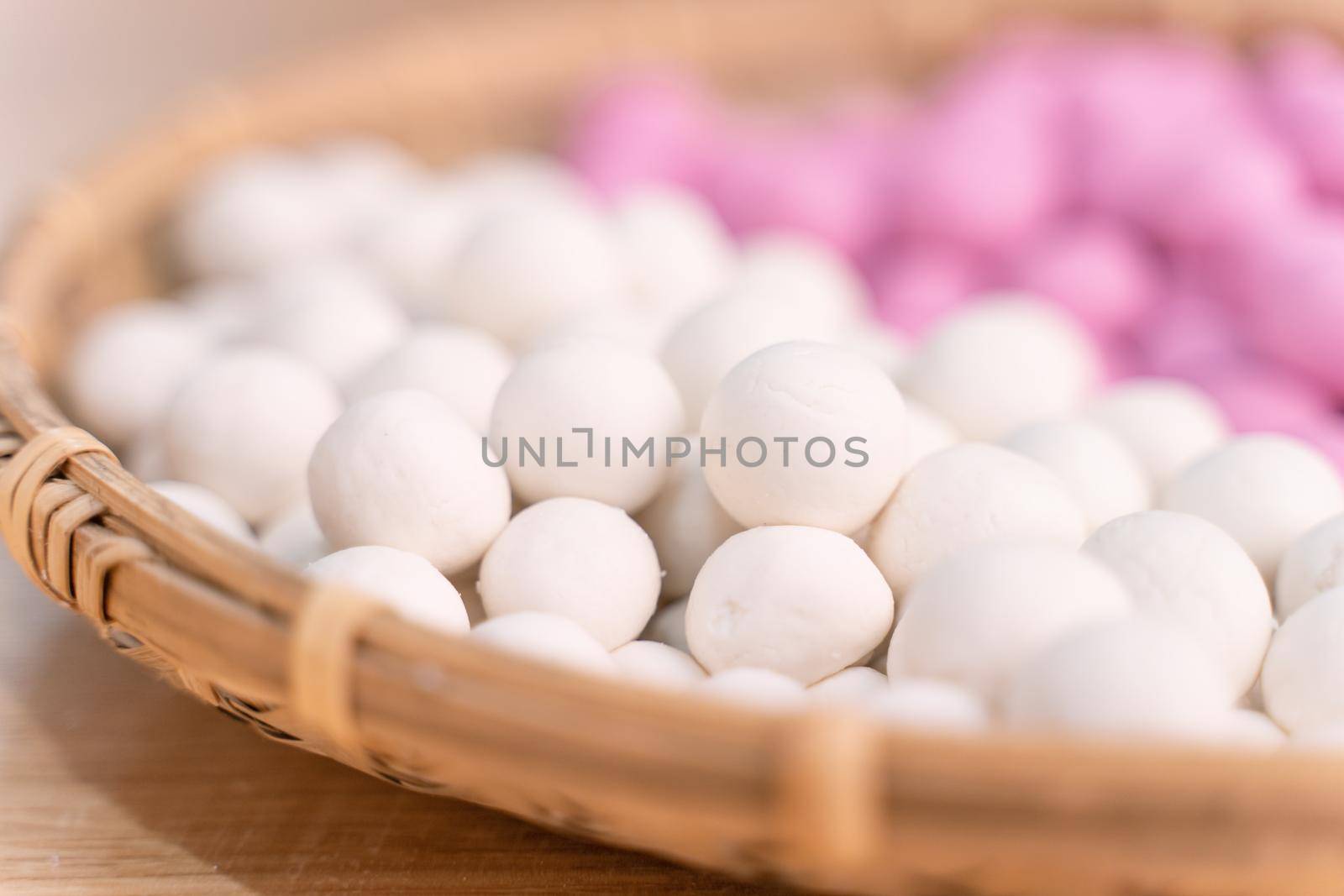 An Asia woman is making Tang yuan, yuan xiao, Chinese traditional food rice dumplings in red and white for lunar new year, winter festival, close up.