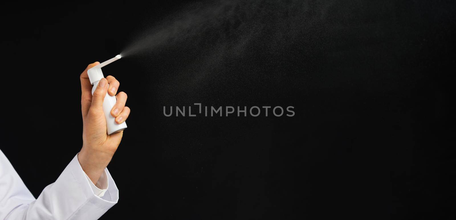 Cropped view of female hand using spray over a black background