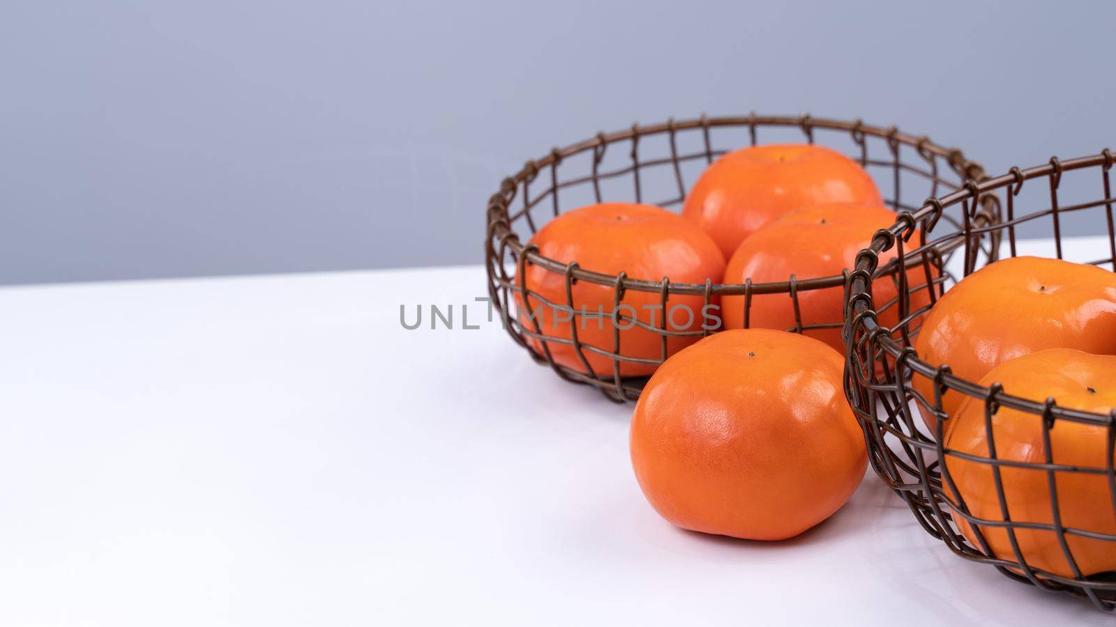 Fresh beautiful sliced sweet persimmon kaki isolated on white kitchen table with gray blue background, Chinese lunar new year design concept, close up.