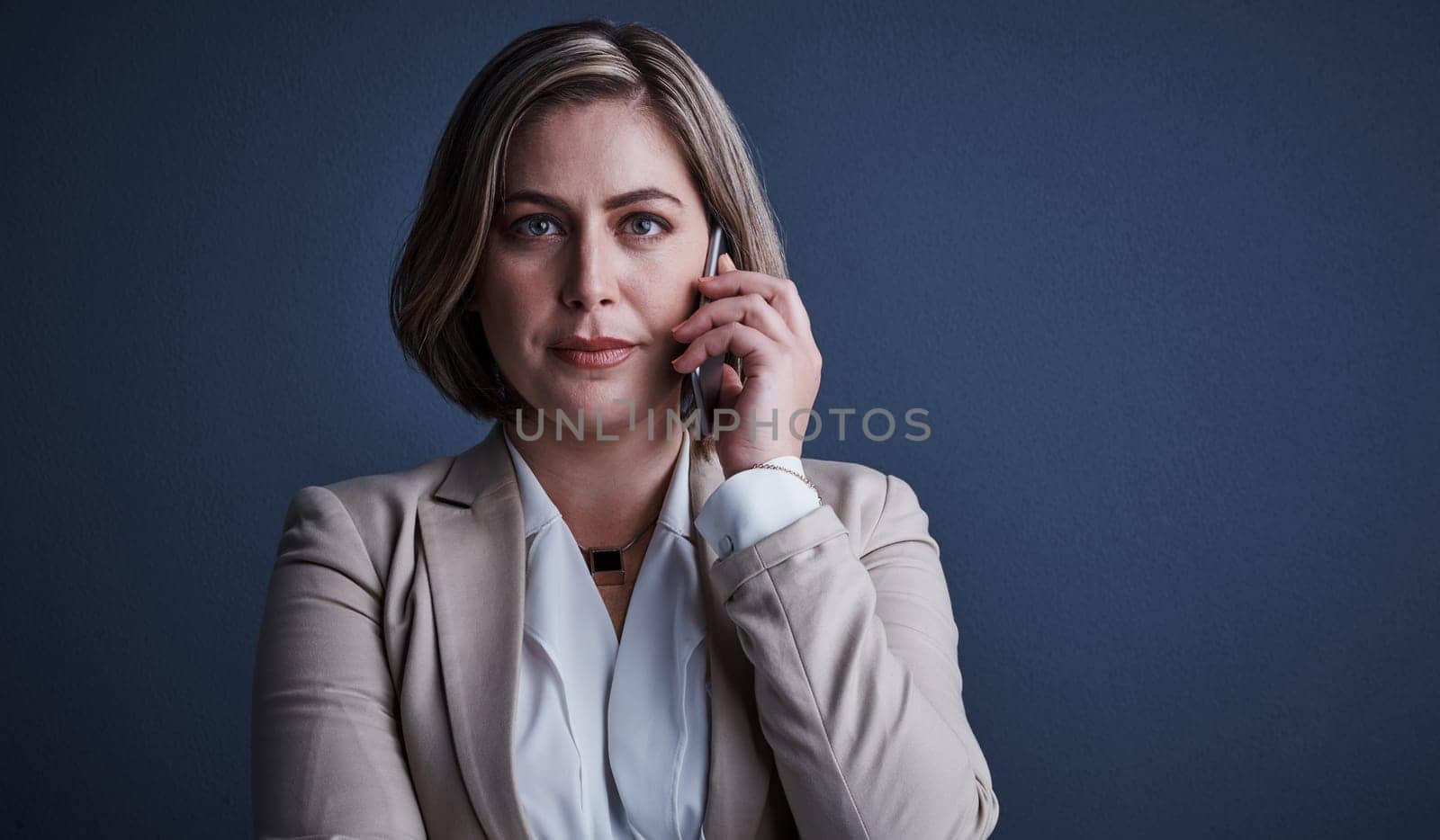 Listening intently. Studio portrait of an attractive young corporate businesswoman making a call against a dark background. by YuriArcurs