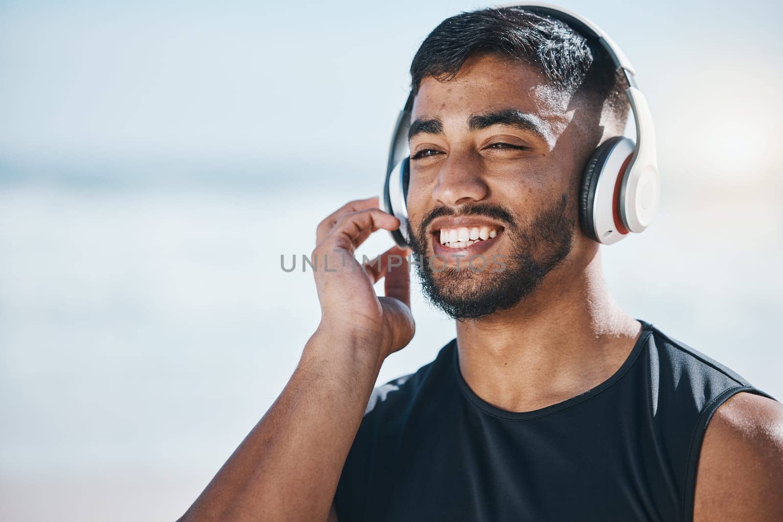 Happy, beach and a man with music for fitness, running motivation and ideas in nature. Smile, wellness and an athlete listening or streaming a podcast while training or exercise vision at the sea by YuriArcurs