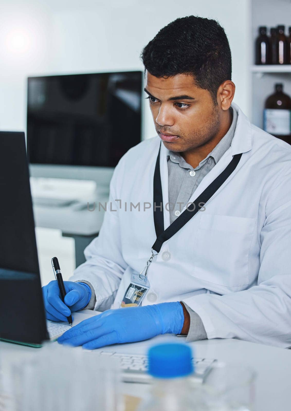 Scientist man, writing and lab computer for medical notes, pharmaceutical report and research with data analysis. Young science expert, pc and paperwork for test, check and innovation in laboratory.