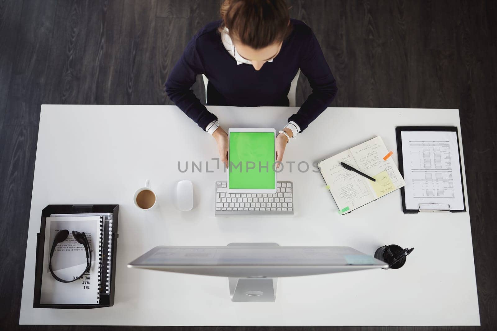 Checking the daily plans. Aerial shot of an unrecognizable young businesswoman sitting at her desk and using her tablet in a modern office. by YuriArcurs