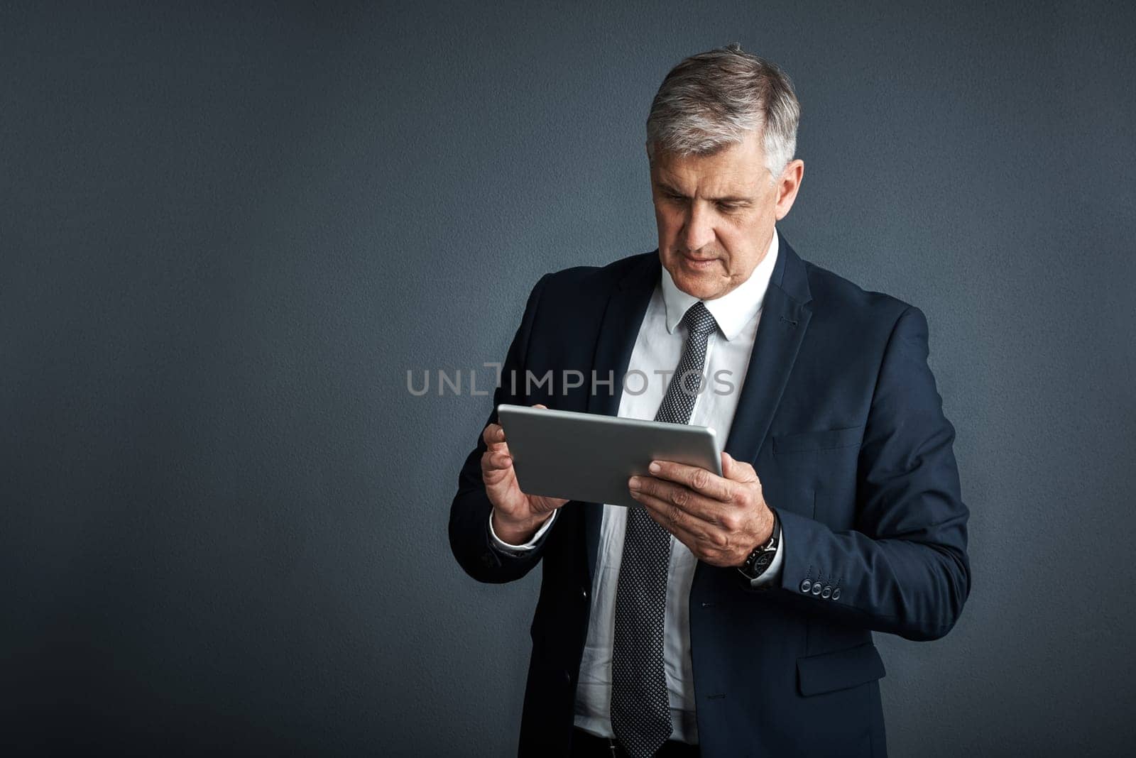 To be successful you must be flexible. Studio shot of a mature businessman using his digital tablet