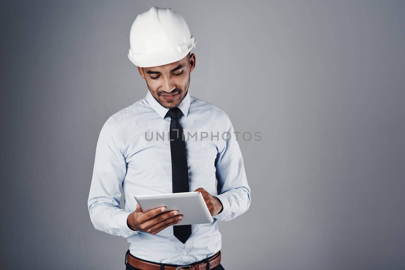 Designing made easy. a well-dressed civil engineer using his tablet while standing in the studio