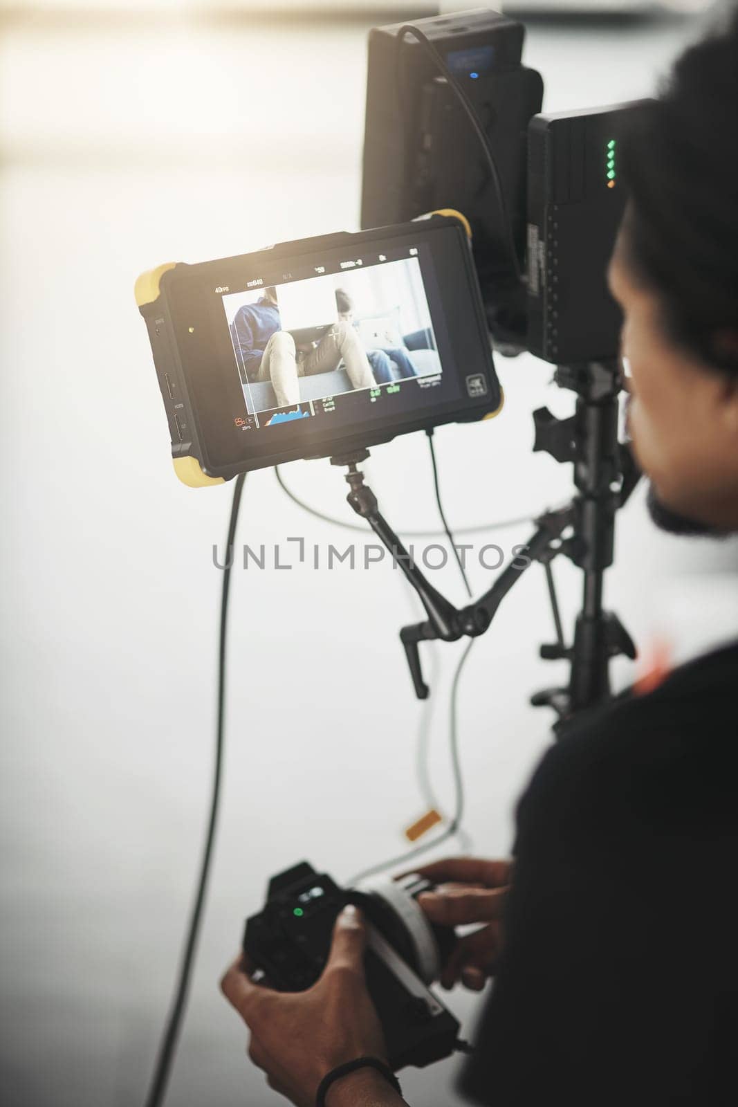 Lets make some magic happen. Behind the scenes over the shoulder shot of an unrecognizable person operating a state of the art video camera inside of a studio. by YuriArcurs