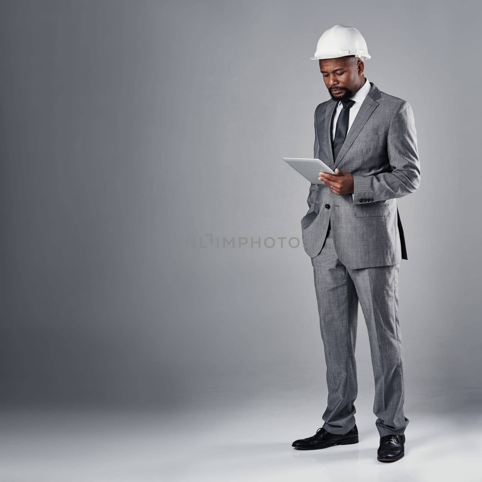 Access to his building plans anytime, anywhere. a well-dressed civil engineer using his tablet while standing in the studio. by YuriArcurs