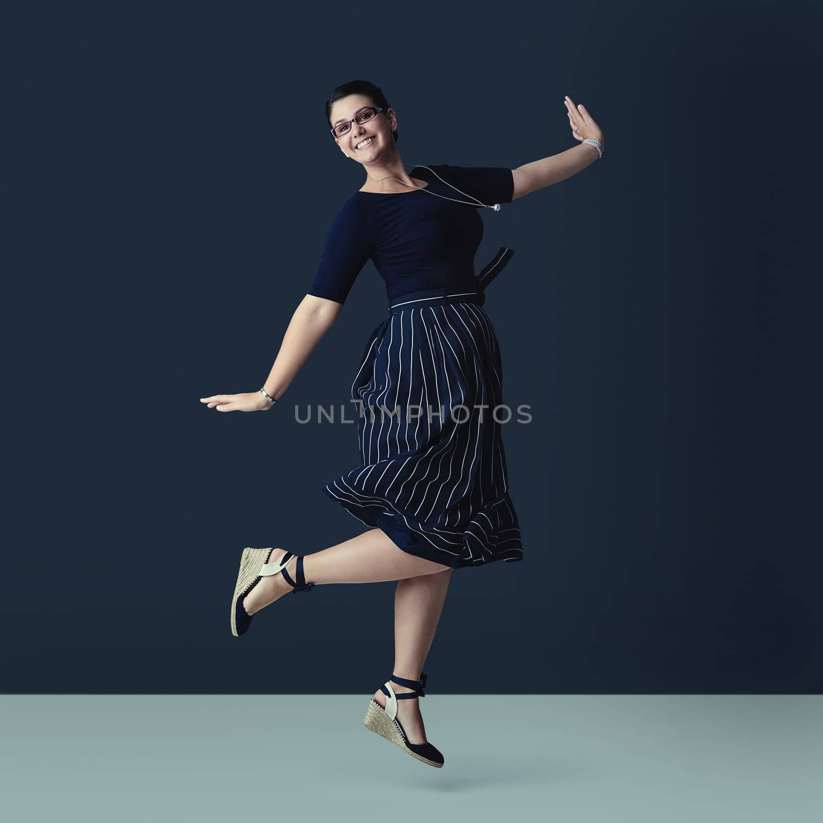 Skipping along towards success. Studio portrait of a corporate businesswoman posing against a dark background. by YuriArcurs