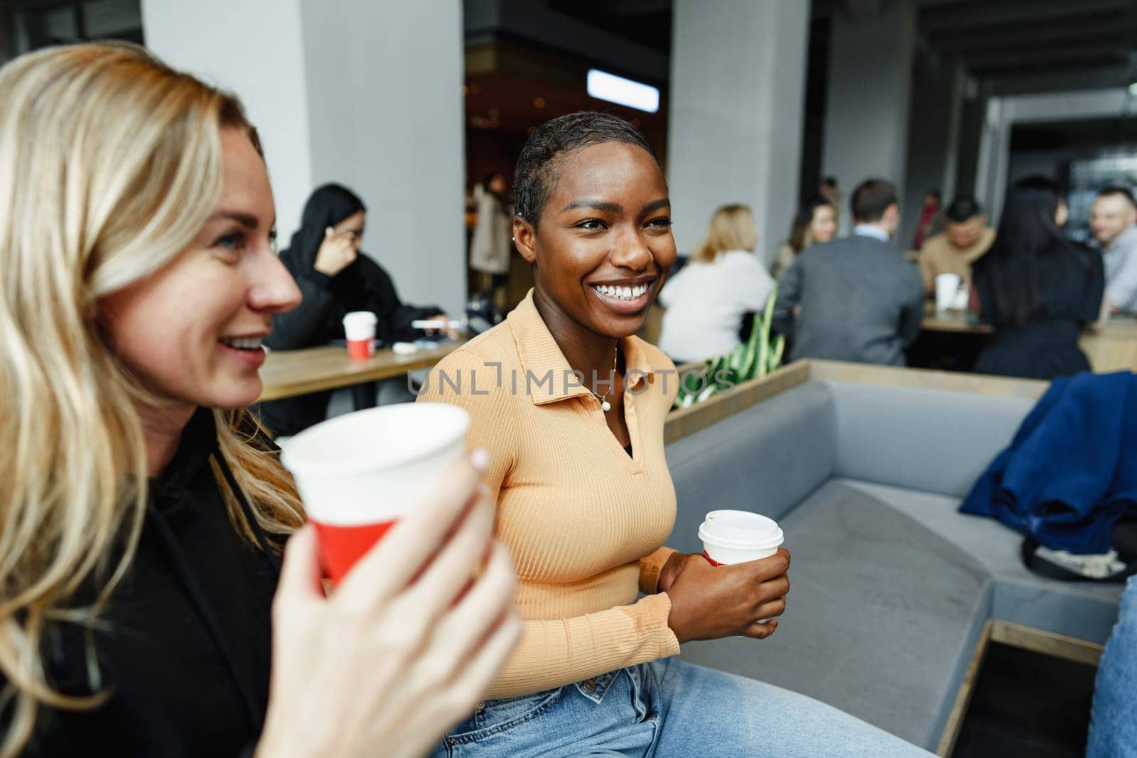 Two young women friends enjoying coffee together in a coffee shop close up