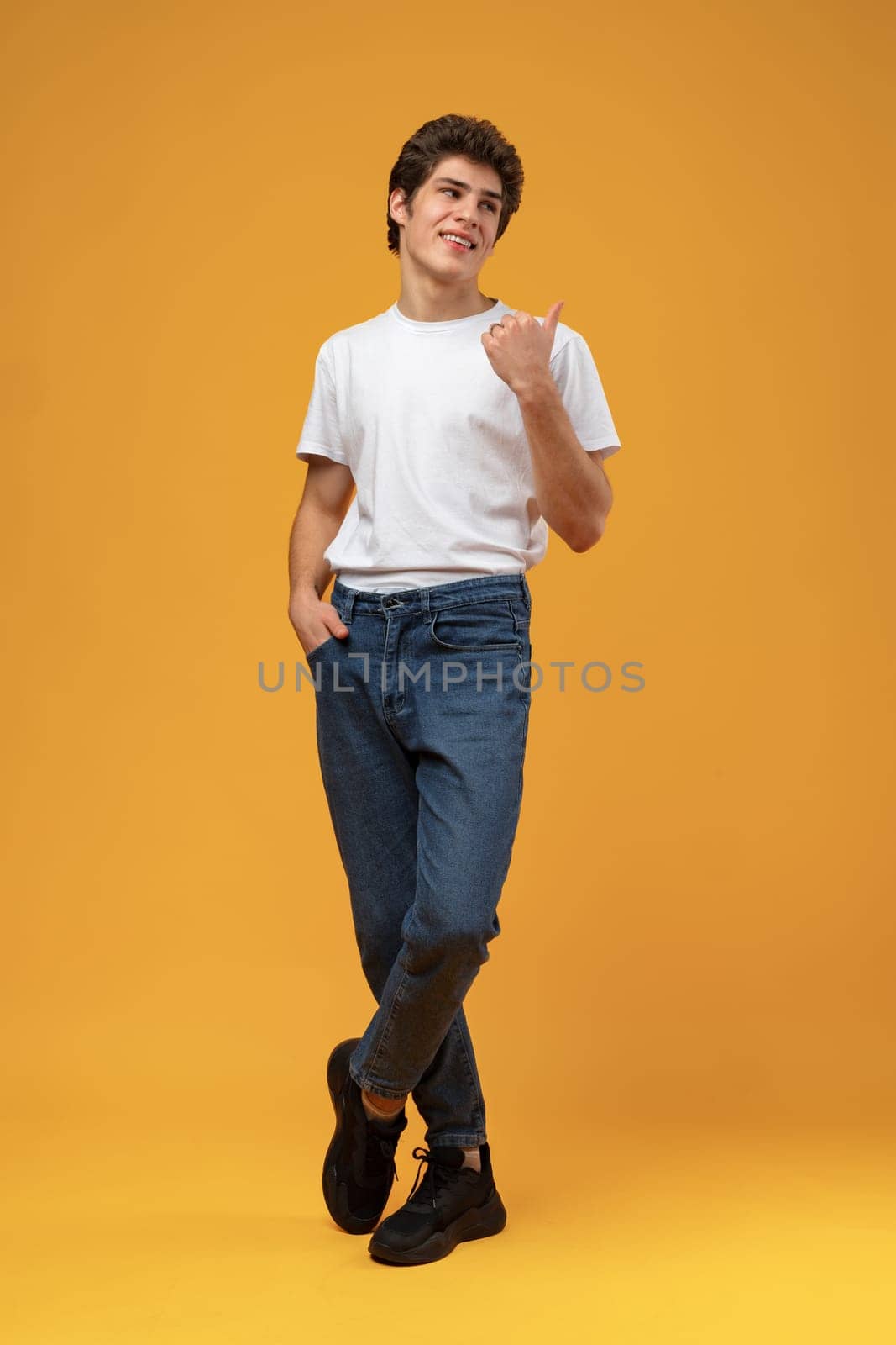 Young handsome man over yellow background pointing to the side copy space