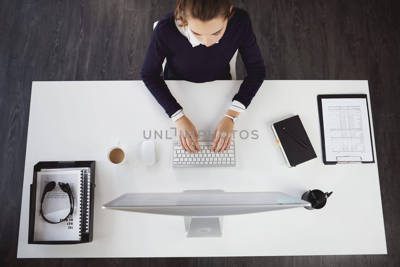 Achieving everything I have ever wanted. Aerial shot of an unrecognizable young businesswoman sitting at her desk and using her computer in a modern office. by YuriArcurs