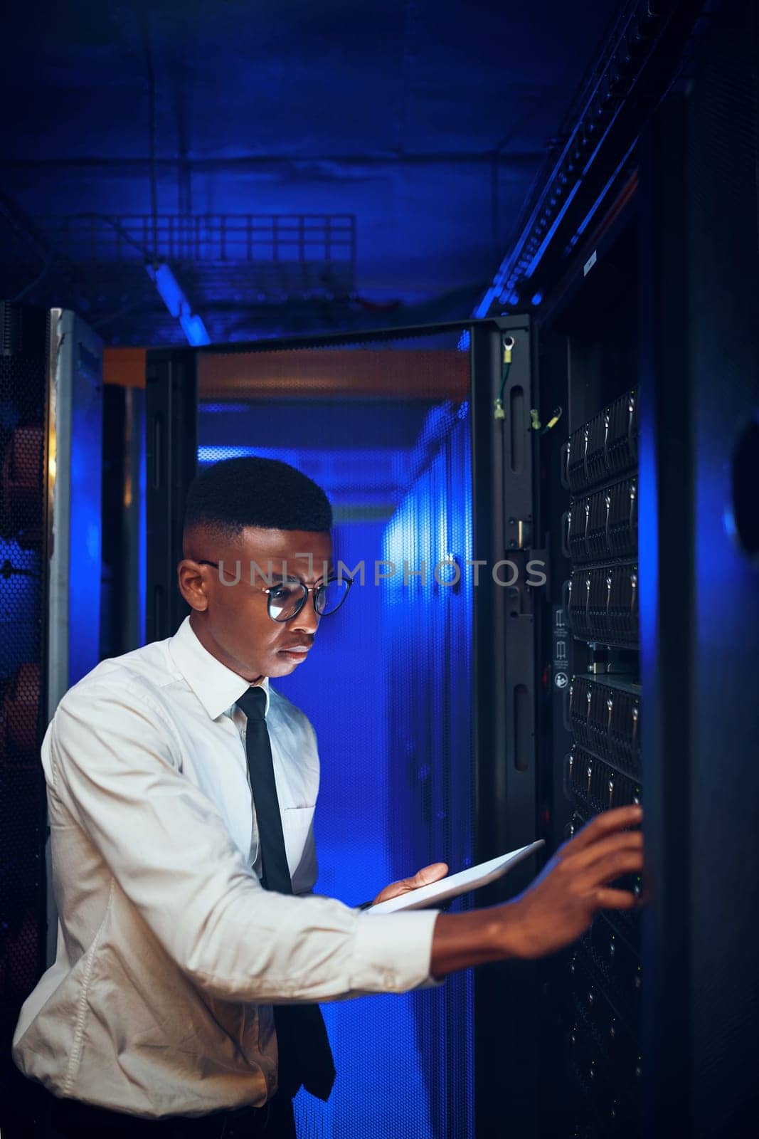 This system is in dire need of an upgrade. a young man using a digital tablet while working in a server room. by YuriArcurs