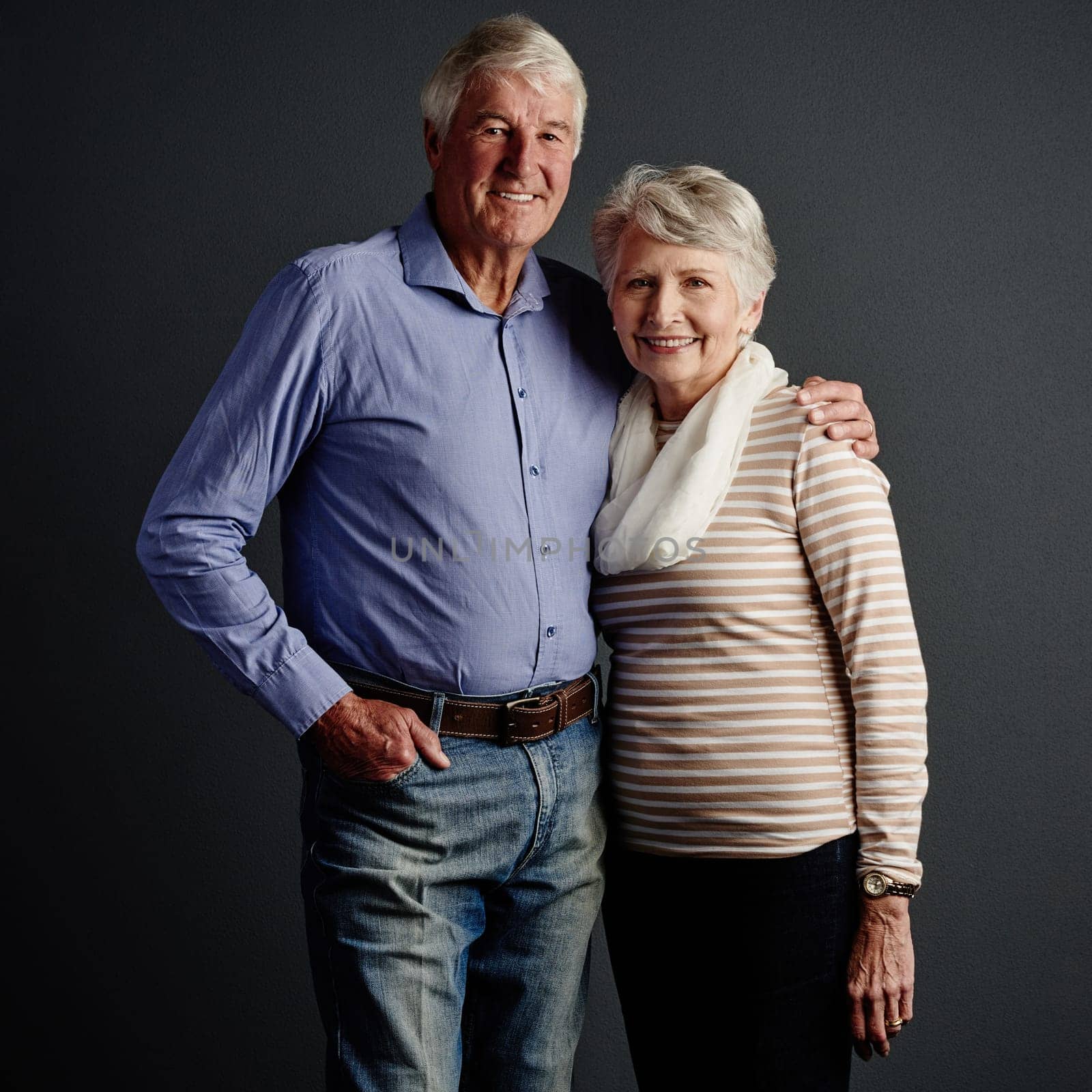 The perfect pair. Studio portrait of an affectionate senior couple posing against a grey background. by YuriArcurs