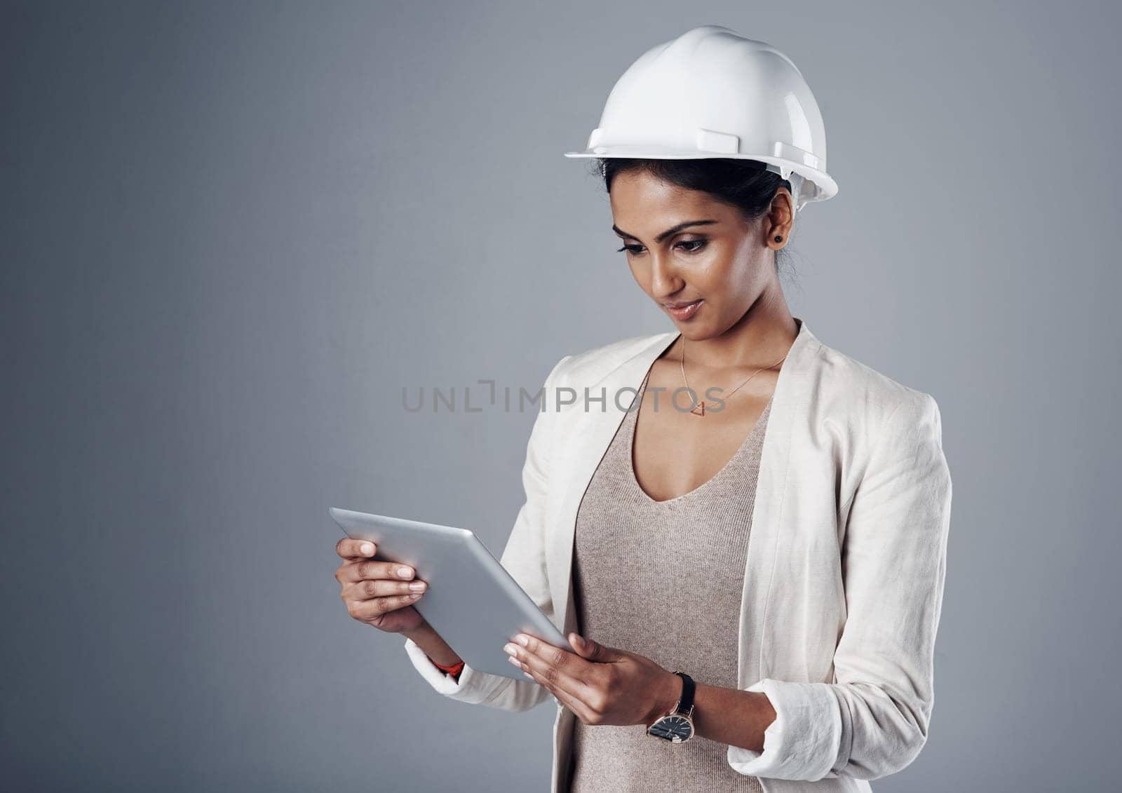 She believes in well-laid plans. a well-dressed civil engineer using her tablet while standing in the studio