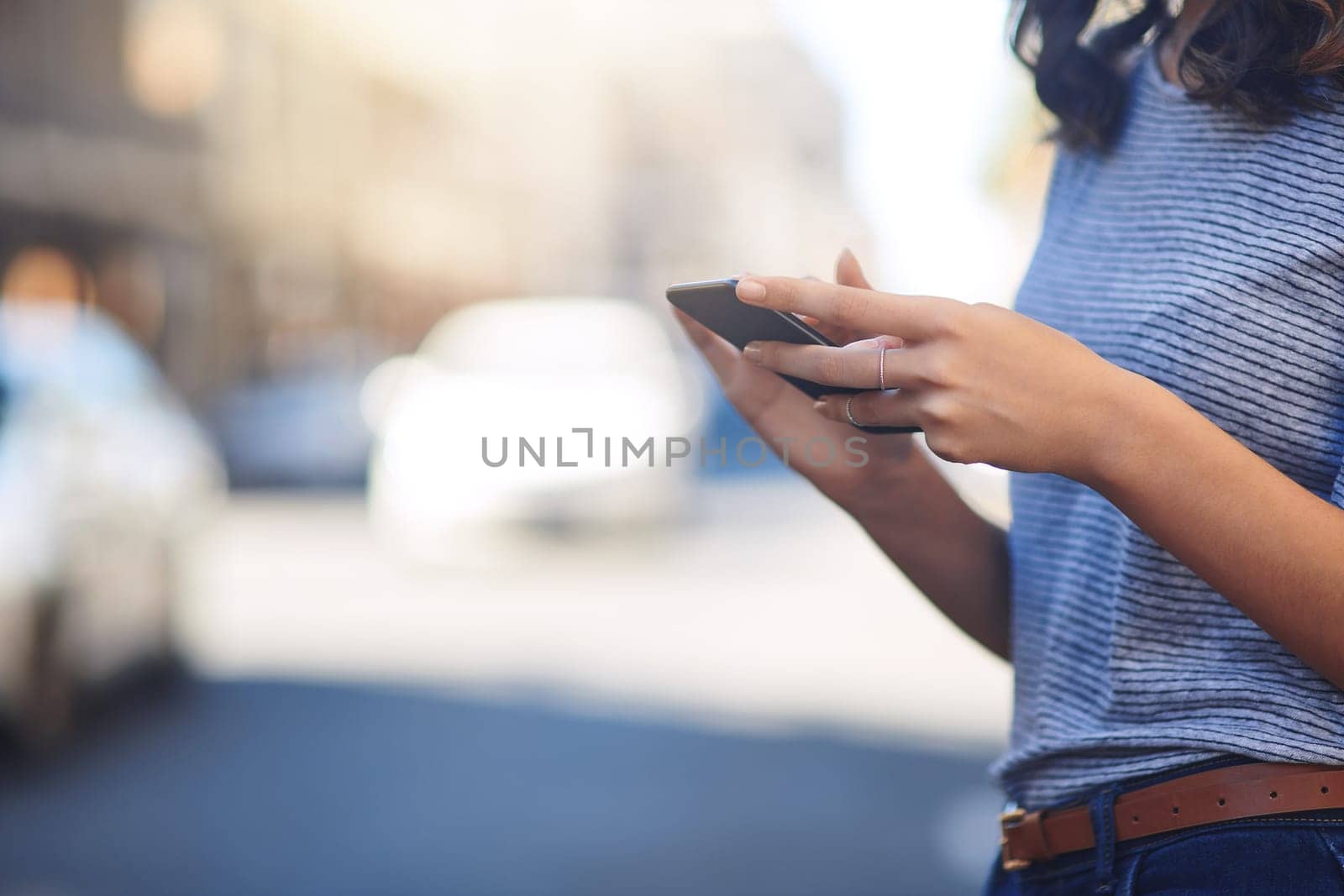 Staying connected has never been easier. an unrecognizable young woman sending text messages while out in the city. by YuriArcurs