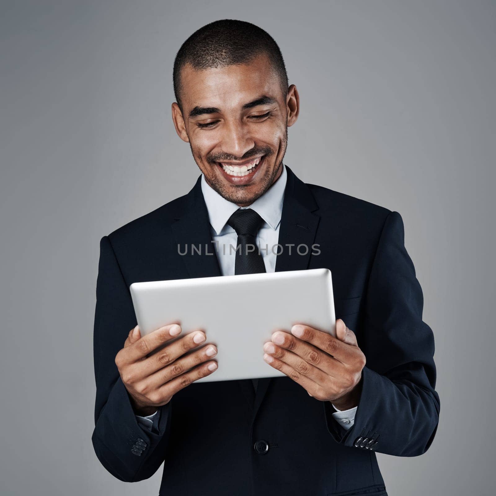 Smart people work smartly. Studio shot of a corporate businessman using a digital tablet against a grey background