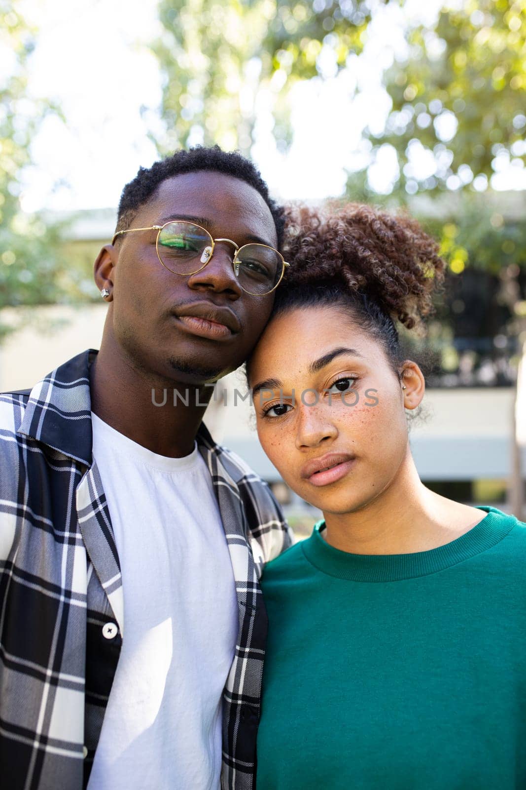 Vertical portrait of African American young couple outdoors looking at camera with serious expression. Relationship concept.