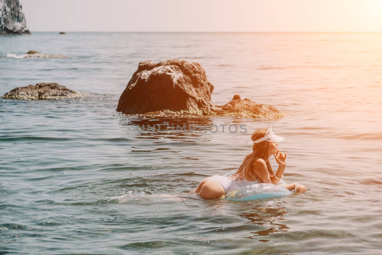 Woman summer sea. Happy woman swimming with inflatable donut on the beach in summer sunny day, surrounded by volcanic mountains. Summer vacation concept