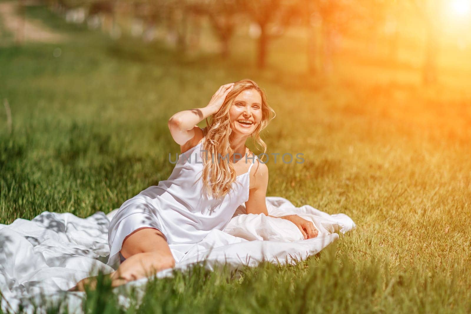 woman garden. she sleeps on a white bed in the fresh spring grass in the garden. Dressed in a blue nightgown