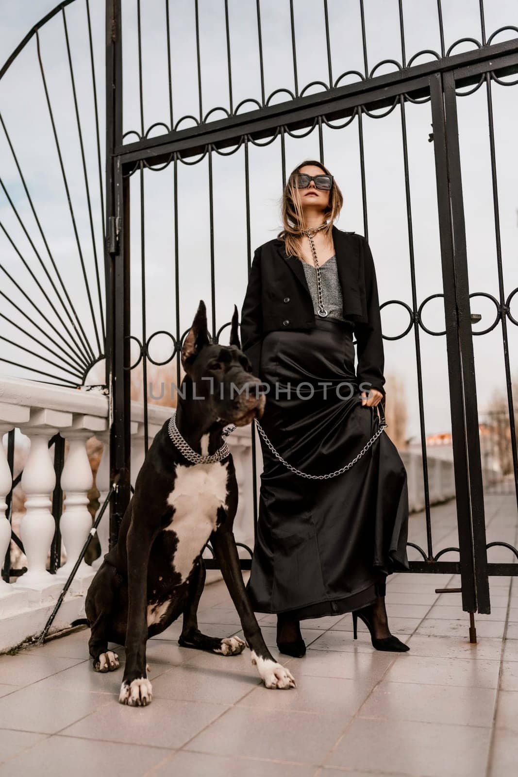 A woman walks with her Great Dane in an urban setting, enjoying the outdoors and the company of her dog. by Matiunina