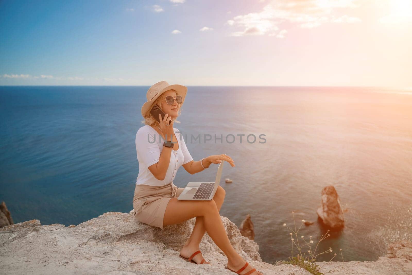 Freelance women sea. She is working on the computer, talking on the phone in the open air with a beautiful view of the sea. The concept of remote work