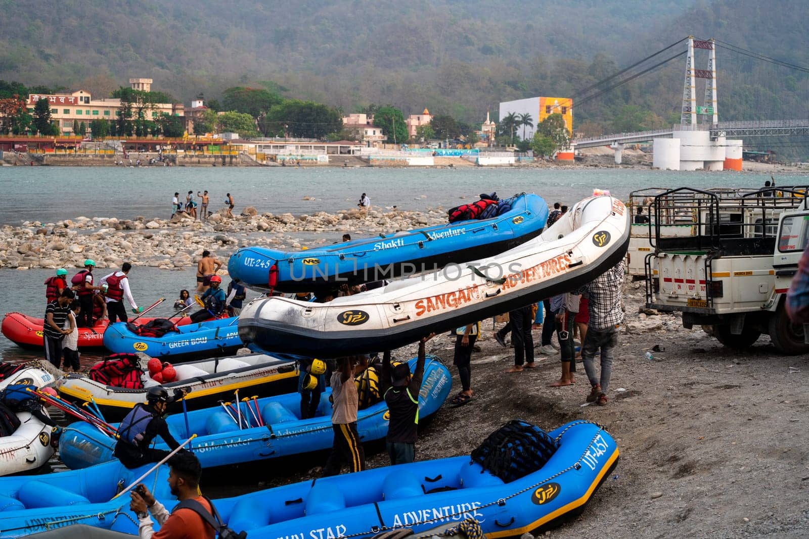 Rishikesh, Haridwar, India - circa 2023: inflatable white water rafts on beach where the adventure sport ends with people taking away rafts and paddles for the next run