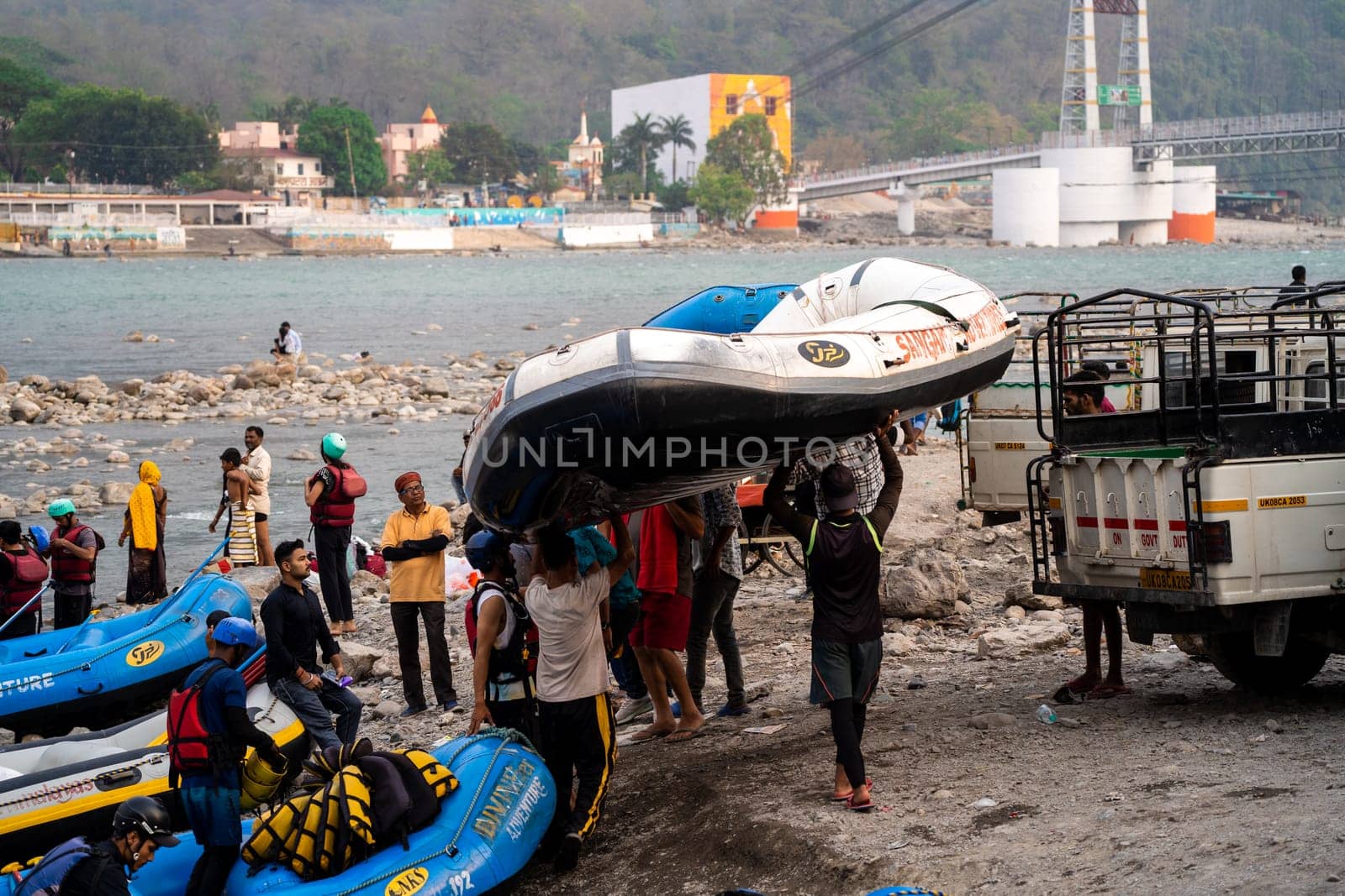 Rishikesh, Haridwar, India - circa 2023: inflatable white water rafts on beach where the adventure sport ends with people taking away rafts and paddles for the next run