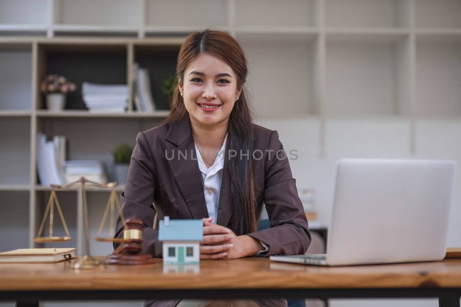 Beautiful Asian businesswoman lawyer sitting at the office holding a pen taking note working on a loan a sample home mallet a laptop