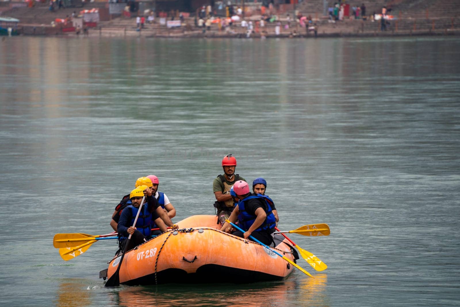 Rishikesh, Haridwar, India - circa 2023: people in helmet jackets rowing raft to shore after white water rafting from shivpuri to rishikesh a popular adventure sport in summers