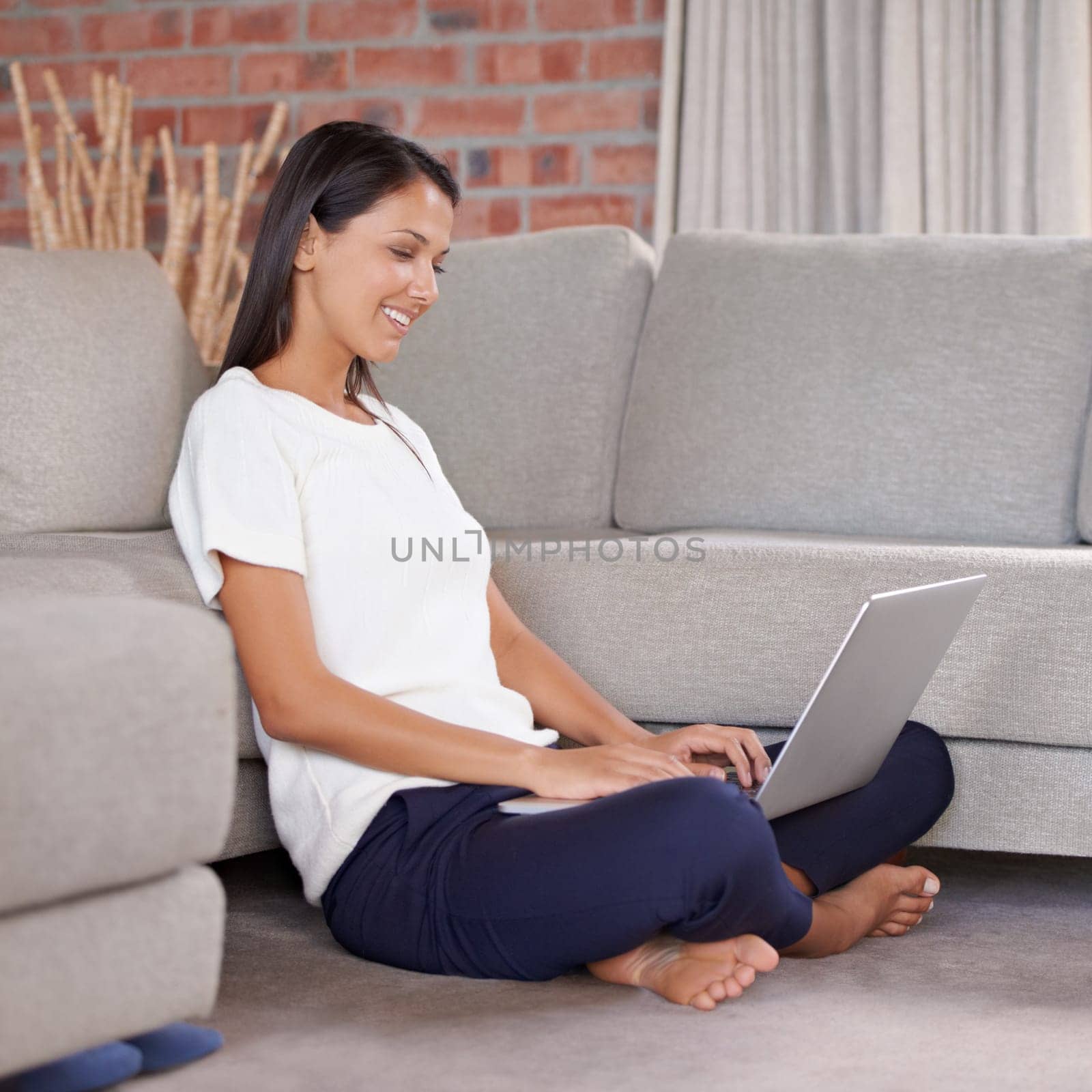 Laptop, smile and a woman typing online in home lounge while streaming online. Happy female person relax on floor for remote work, studying and research or email with internet connection in a house.