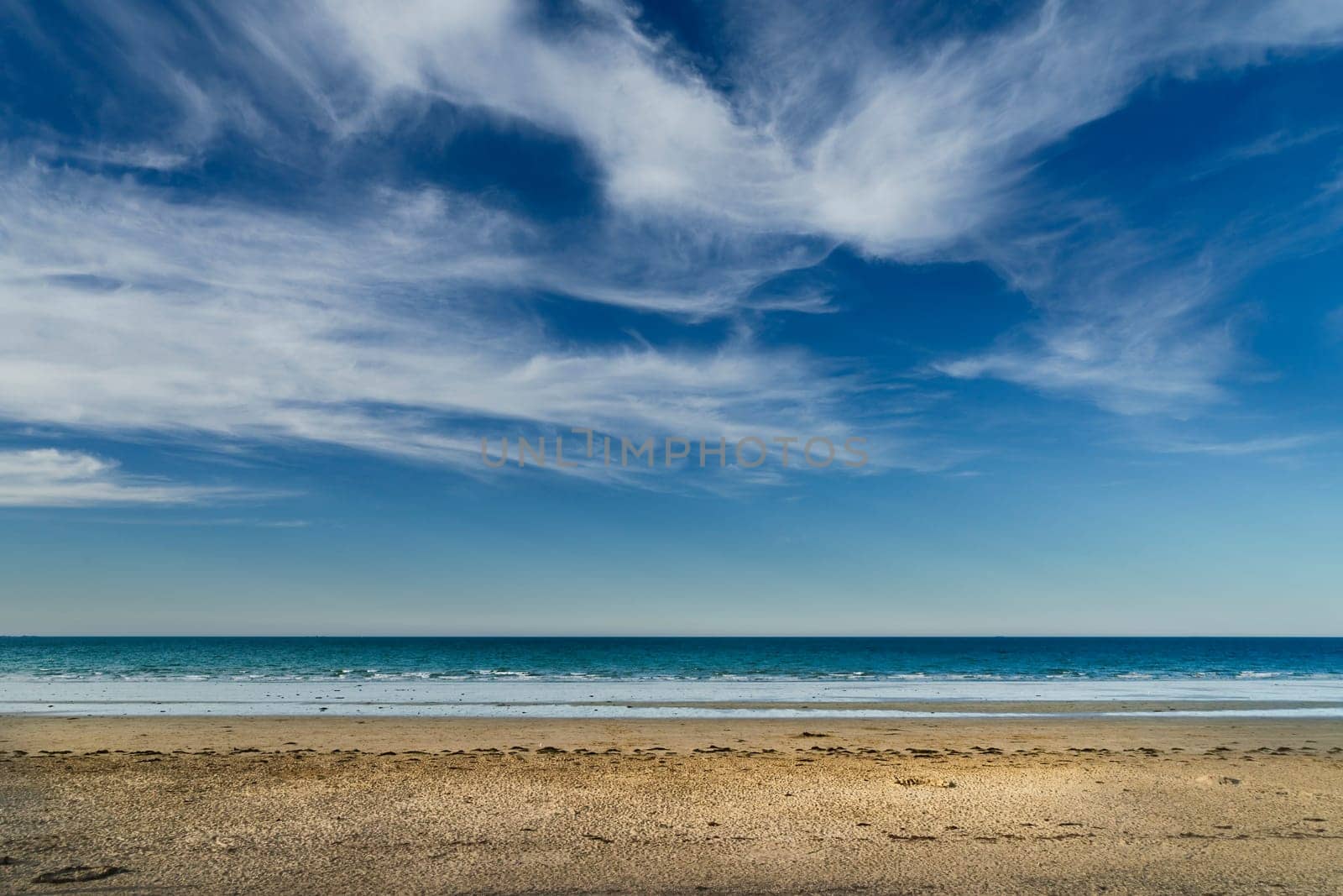 Landscape of an uncrowded beach with white clouds over blue sky in Brittany, France. by csbphoto