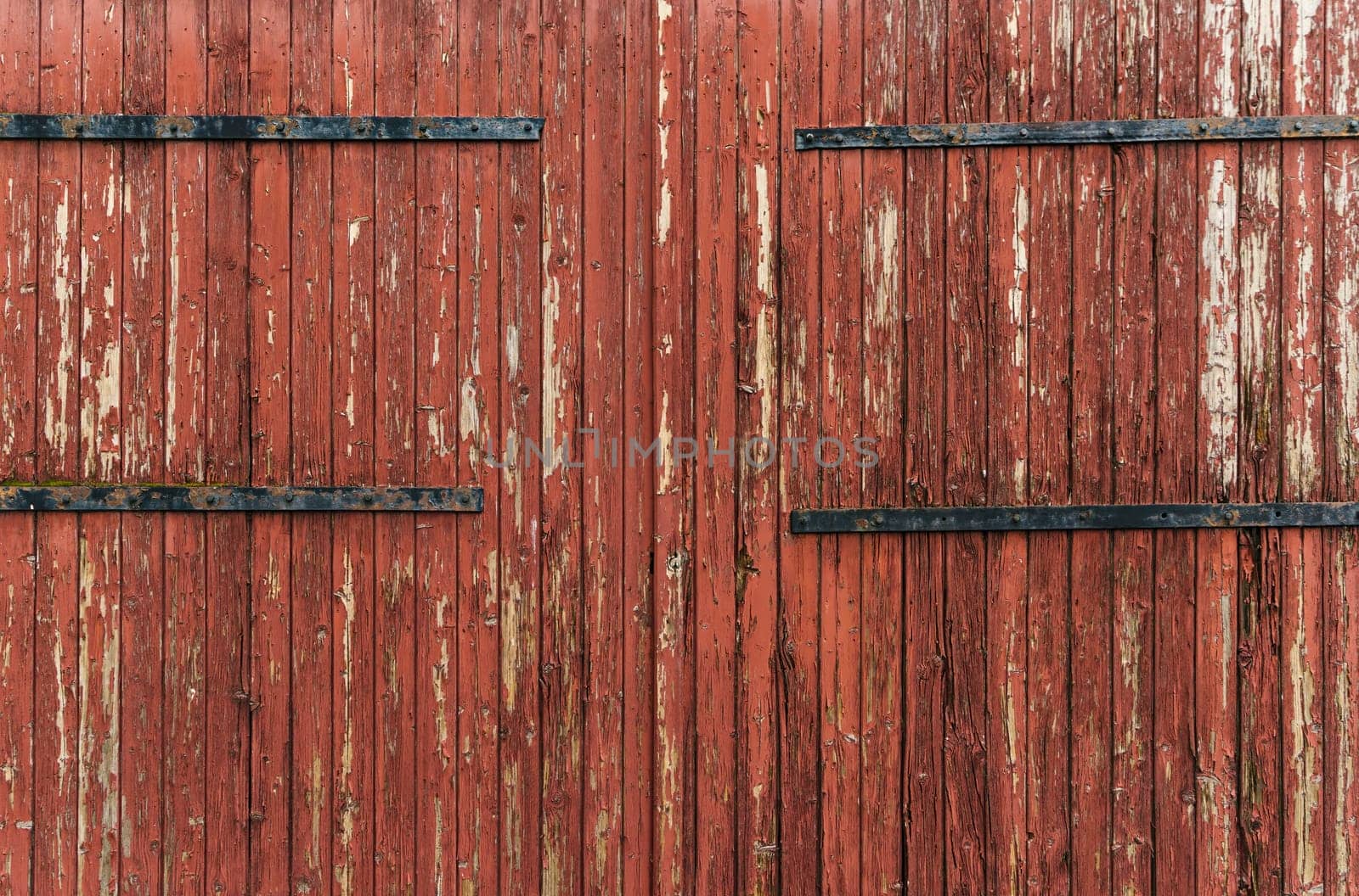 Detail of antique wooden door in red tones, with lots of texture and pickled paint. Concept for backgrounds and textures.