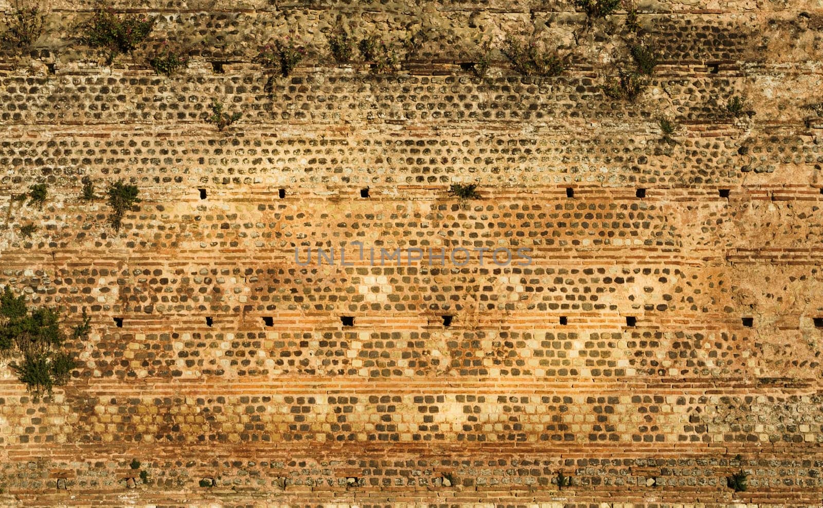 View of the ancient Gallo-Roman wall of Le Mans in France, built with stones in warm tones. by csbphoto