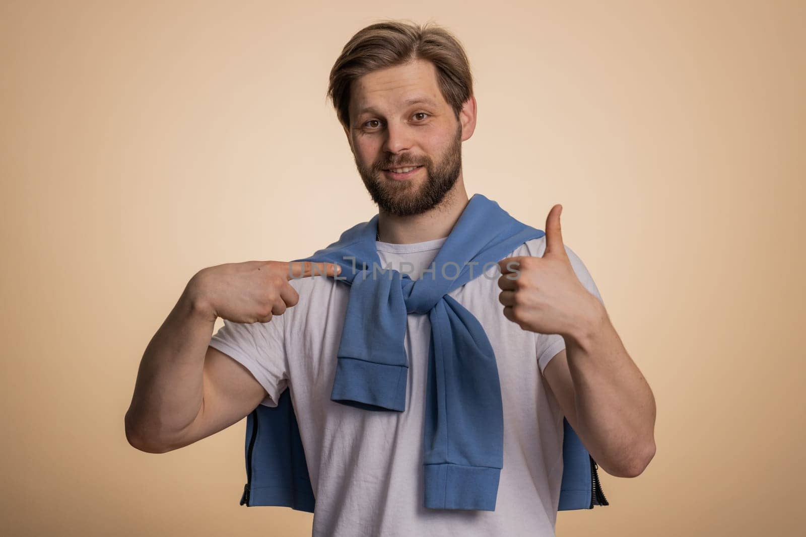 I am the best, choose me. Young excited caucasian man winner feeling very proud pointing hisself, looking self-confident, overjoyed by success. Handsome adult guy isolated on studio beige background