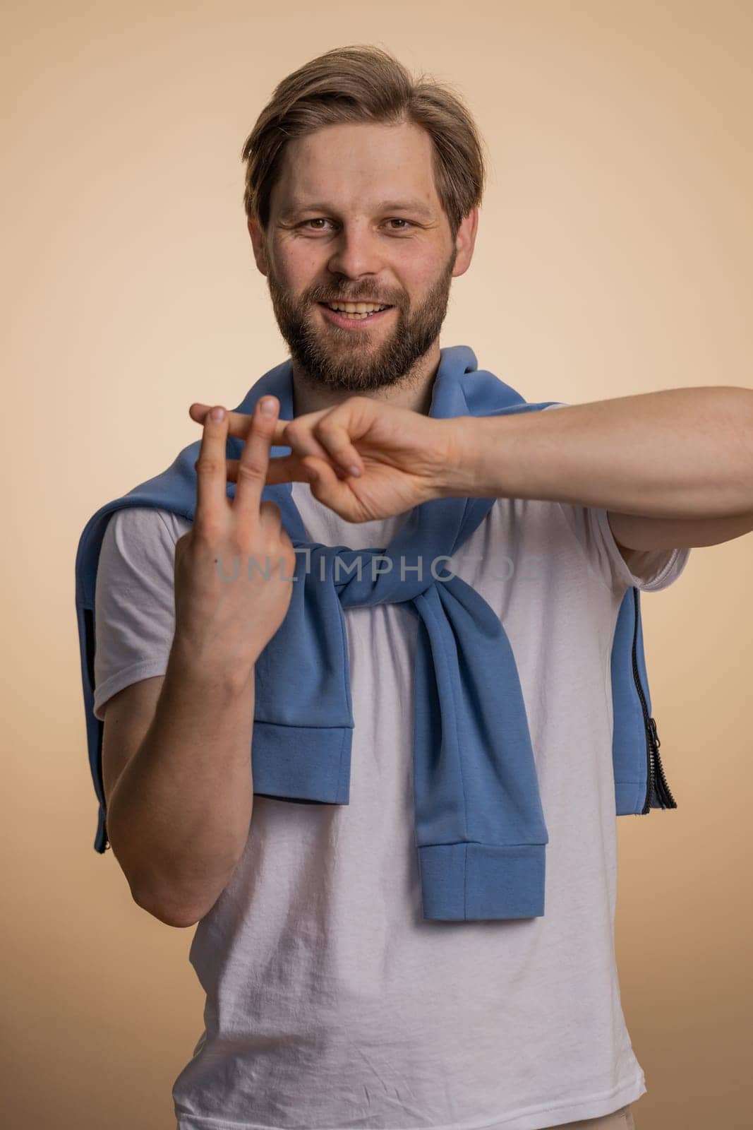 Cheerful caucasian man showing hashtag symbol with hands, likes tagged message, popular viral content, sign to follow internet online trends. Young bearded guy isolated on beige studio background