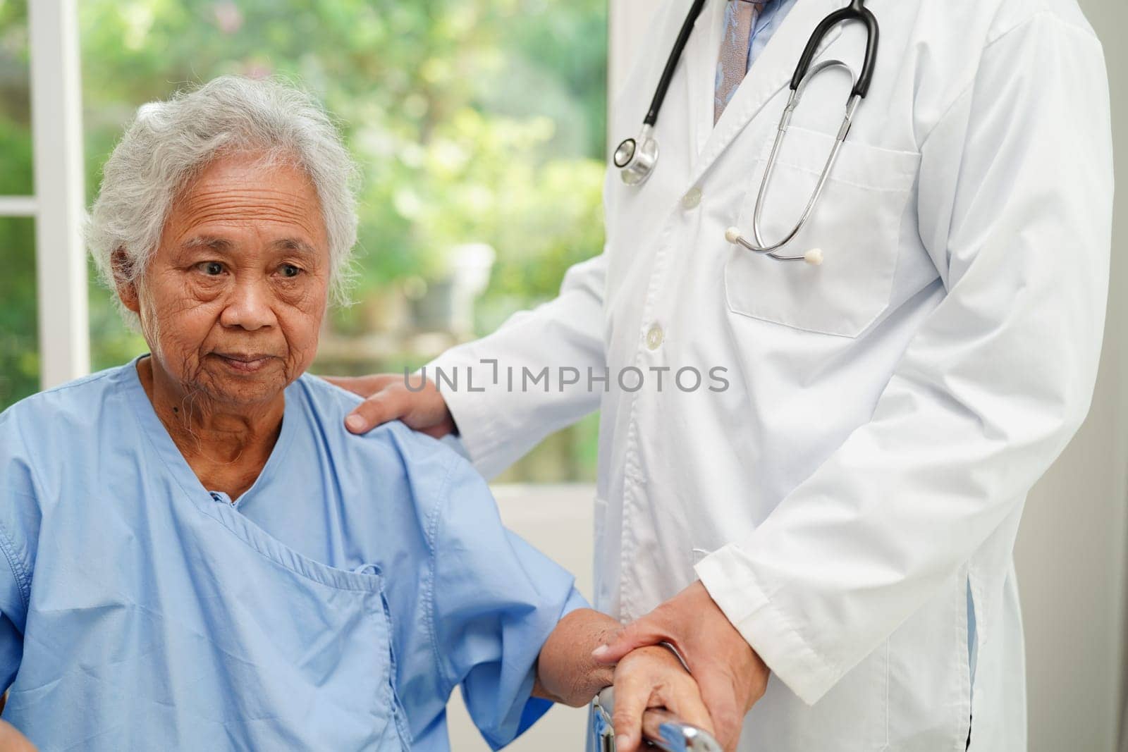 Doctor help Asian elderly woman disability patient walk with walker in nursing hospital, medical concept.